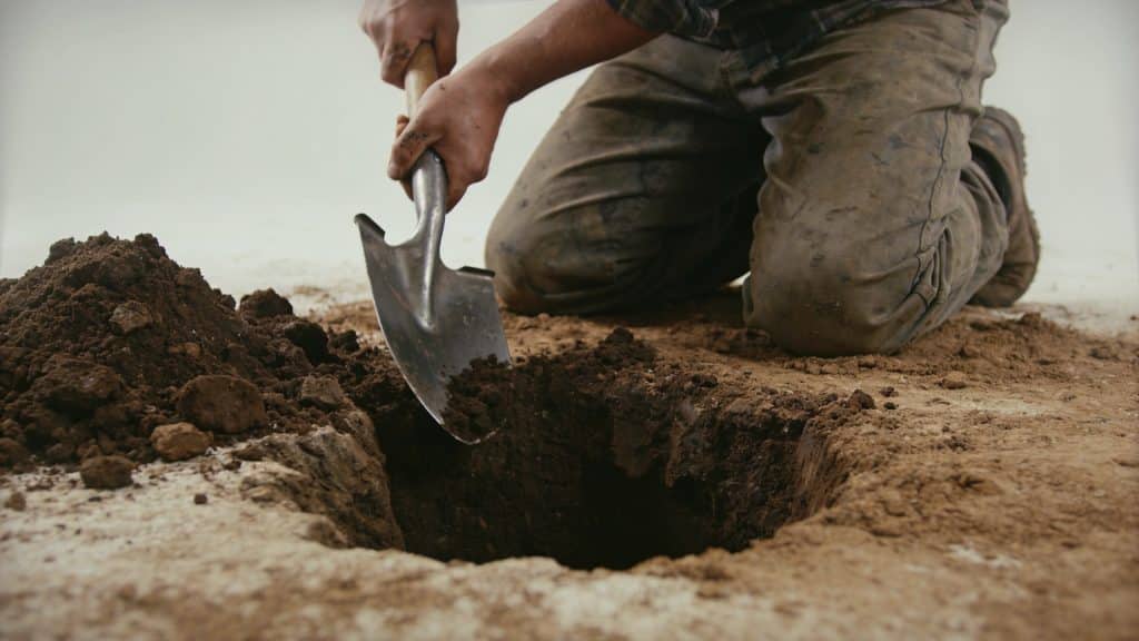 Jardinier creusant large trou profond dans terre