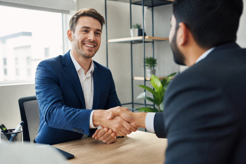 Candidat souriant en costume serrant la main du recruteur