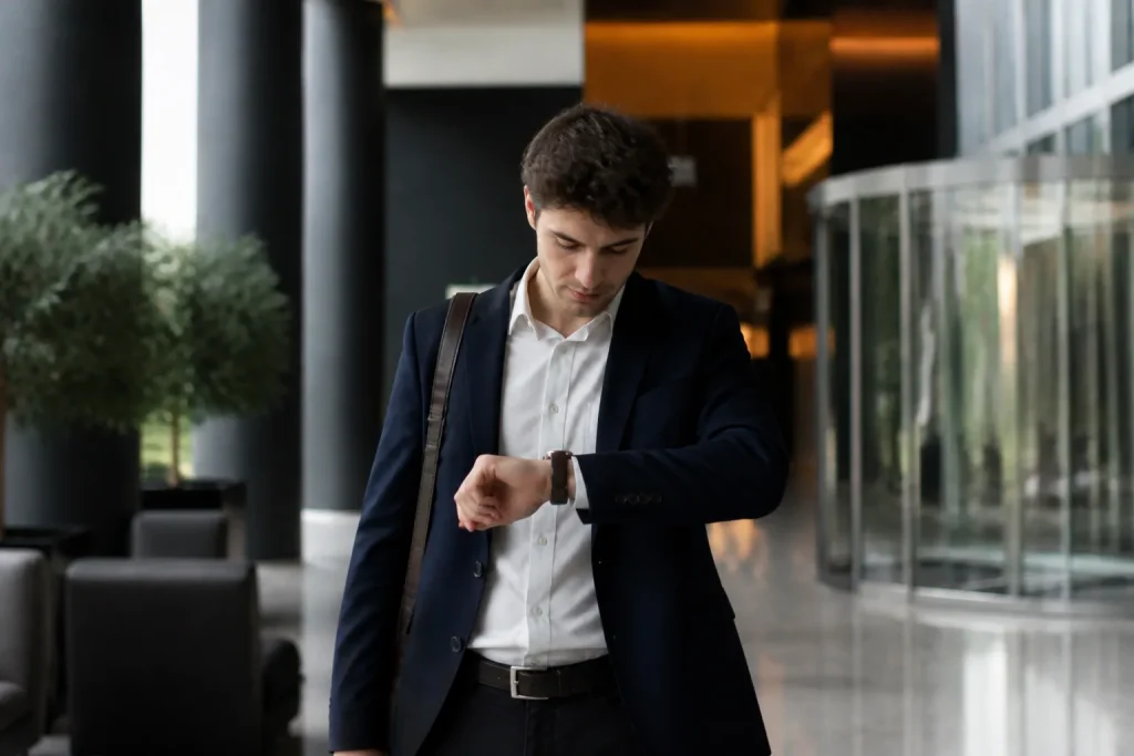 Jeune homme regardant sa montre dans un hall moderne