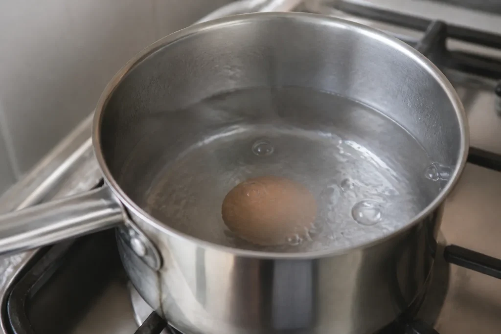 Oeuf entier pose dans une casserole d'eau fumante